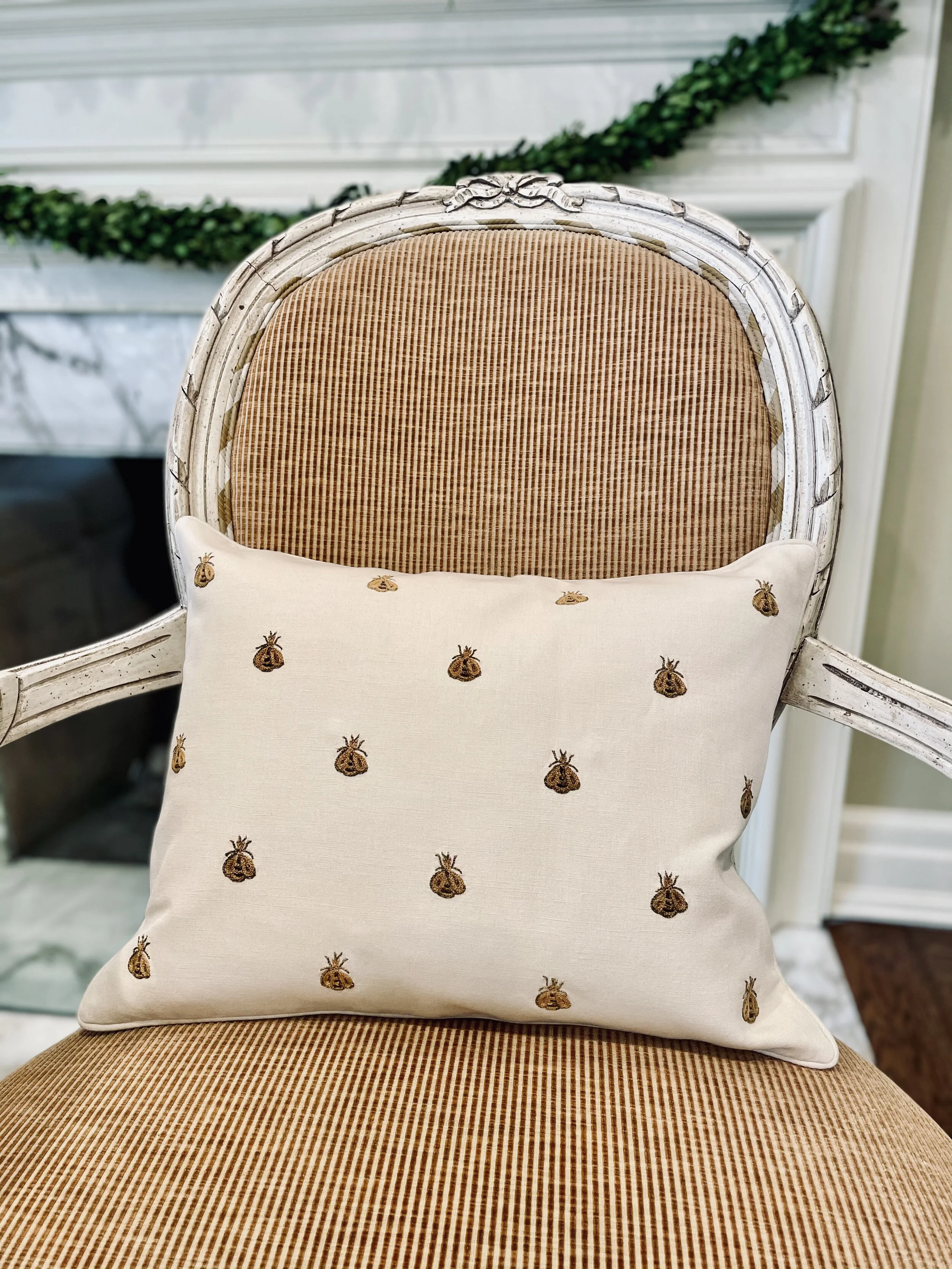 Gold-on-cream bee pillow on a French cane chair